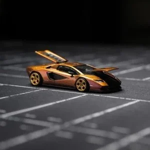 Ein orange-gelbes Spielzeugauto mit aufklappbaren Türen auf einem dunklen Hintergrund.
